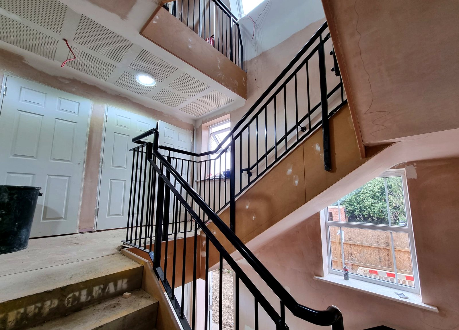 Metal bar-infill balustrade with wall-mounted handrail on an apartment communal stair, Radlett